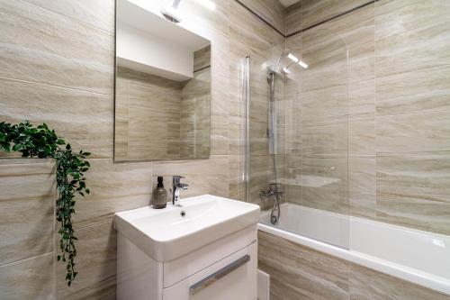 a bathroom with a white sink and a shower at Skylark - Cairo Penthouse cu Jacuzzi si Vedere la Munte in Braşov