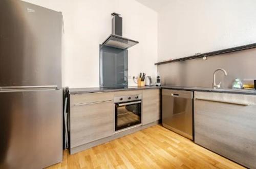 une cuisine avec un réfrigérateur en acier inoxydable et du parquet dans l'établissement Nouveau T2 Centre Historique, à Thiers