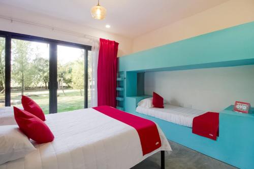 two beds in a room with red and blue at Capital O Hacienda Filadelfia, El Atorón, Irapuato in Irapuato