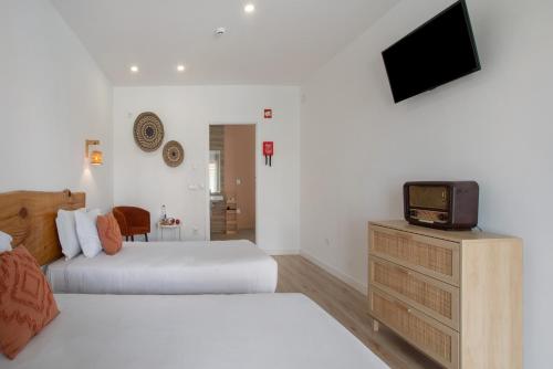 a bedroom with two beds and a tv on a dresser at Quinta dos Raposos- Nazaré Portugal in Nazaré