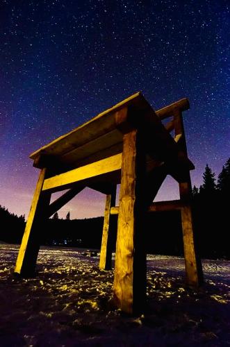 a wooden bench sitting in the snow at night at Horská Bouda v Obřím Dole in Pec pod Snezkou