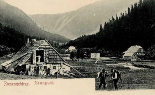 an old photo of two people standing in front of a house at Horská Bouda v Obřím Dole in Pec pod Snezkou