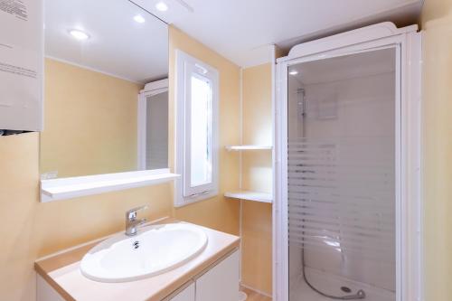une salle de bain avec un lavabo et une douche dans l'établissement Mobilhome Calvi, à Bouzic
