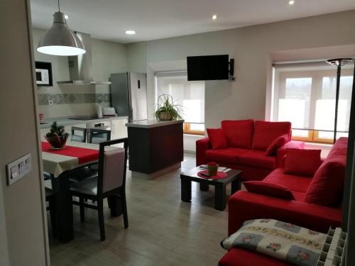 a living room with a red couch and a kitchen at Casa Castillo II in Arenas de Iguña