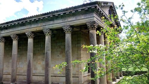 a large stone building with columns and trees at Casa Castillo II in Arenas de Iguña