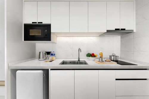 a white kitchen with a sink and a microwave at Citadines Guanghua Chengdu in Chengdu