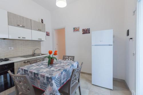 Una cocina con una mesa con un jarrón de flores encima. en Luna rossa salento - Casa Rossa, en Porto Cesareo