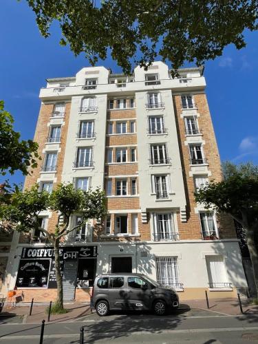 une voiture garée devant un grand immeuble dans l'établissement Quiet City Center!, à Gentilly