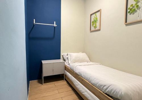 a small room with a bed and a blue wall at ITCC Manhattan by IGVC in Penampang