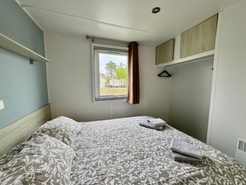 ein kleines Schlafzimmer mit einem Bett und einem Fenster in der Unterkunft Un toit sur le bassin bungalow camping les viviers in Lège-Cap-Ferret