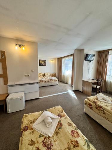 a hotel room with two beds and a desk at Хотел Добринище in Dobrinishte