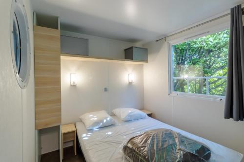 une petite chambre avec un lit et une fenêtre dans l'établissement Mobilhome O’Hara 834T, à Bouzic
