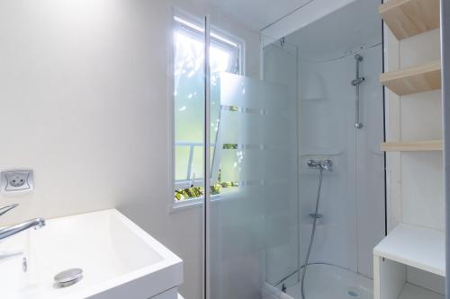 une salle de bain blanche avec une douche et un lavabo dans l'établissement Mobilhome O’Hara 834T, à Bouzic