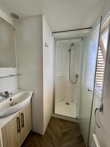 une salle de bain blanche avec une douche et un lavabo dans l'établissement Un toit sur le bassin bungalow camping les viviers, à Lège-Cap-Ferret
