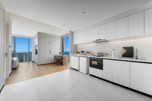 a kitchen with white cabinets and a living room at Citadines Guanghua Chengdu in Chengdu