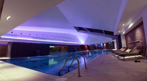 a swimming pool in a hotel with couches at Parklands Hotel & Country Club in Newton Mearns