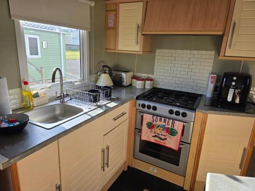 a kitchen with a stove top oven next to a sink at Todber Valley Parkdeane resorts in Gisburn
