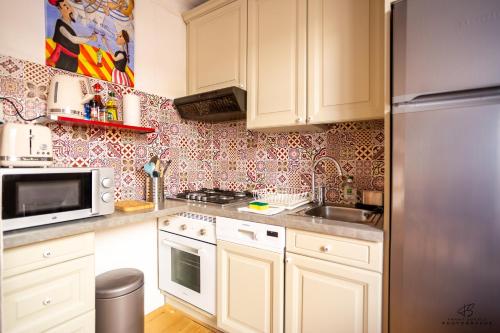 une cuisine avec des armoires blanches et un réfrigérateur en acier inoxydable dans l'établissement Le Conflent WIFI Terrace, à Collioure