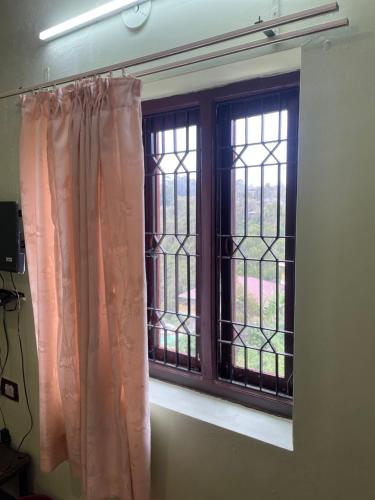 una ventana con cortinas rosas en una habitación en i2 residency, en Kodaikanal
