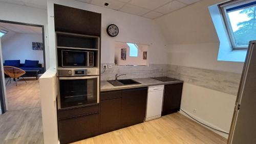 a kitchen with a sink and a microwave at La Bonnerie-Le Pupitre La Bouëxière in La Bouexière