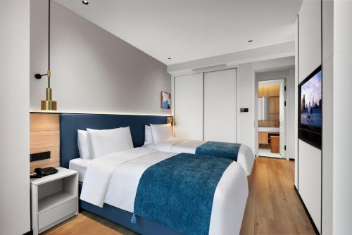 a bedroom with a large bed and a tv at Citadines Guanghua Chengdu in Chengdu