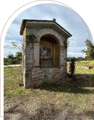 a brick building with a window in a field at L'edicola di Ripalvella in San Venanzo