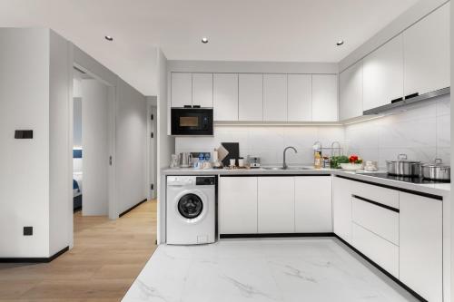 a white kitchen with a washing machine in it at Citadines Guanghua Chengdu in Chengdu