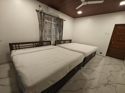 two twin beds in a bedroom with a window at The Mango Valley Nature's Stay in Alibag