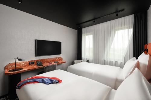 a hotel room with two beds and a flat screen tv at TRIBE Budapest Airport in Budapest