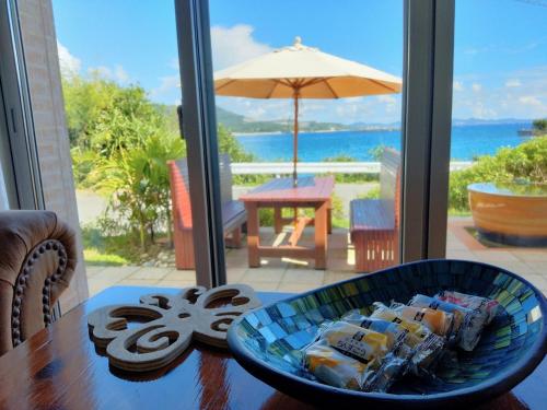 a bowl of food on a table with a view of the ocean at Papillon パピヨン 瀬底島オーシャンビューゲストハウス in Motobu