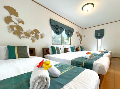 a room with three beds with towels on them at Papillon パピヨン 瀬底島オーシャンビューゲストハウス in Motobu