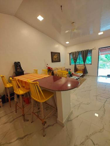 a dining room with a wooden table and yellow chairs at The Mango Valley Nature's Stay in Alibag