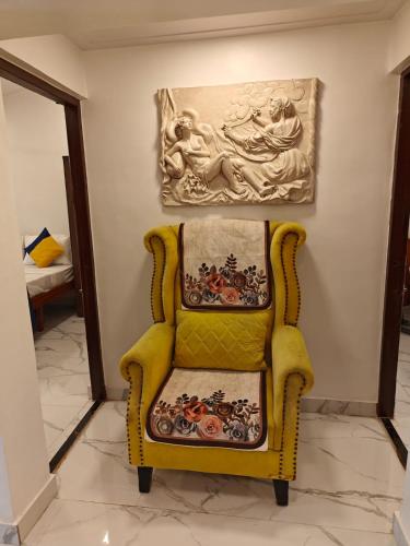 a yellow chair in a room with a painting on the wall at The Mango Valley Nature's Stay in Alibag