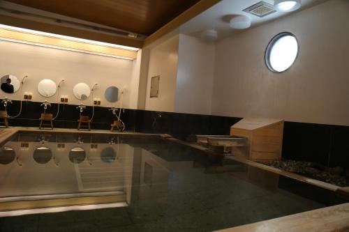 a bathroom with urinals and sinks and a window at Hotel Plaza Arakawaoki in Tsuchiura