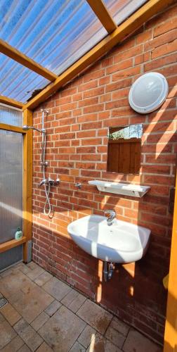a bathroom with a sink and a brick wall at Ferienbungalows am See in Altfriesack