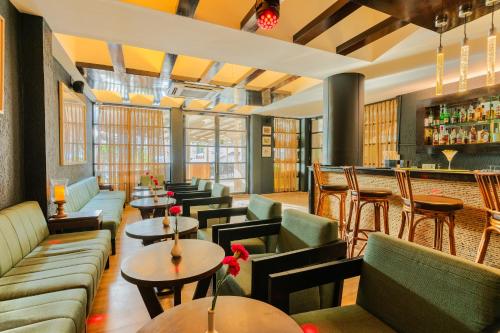 a restaurant with couches and tables and a bar at Whispering Palms Beach Resort in Candolim