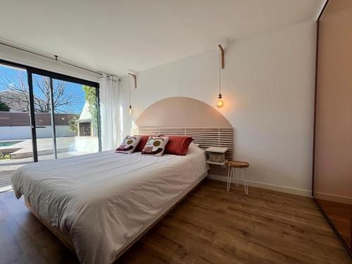 une chambre avec un grand lit et une grande fenêtre dans l'établissement Villa avec piscine au charme authentique et naturel, à Baillargues