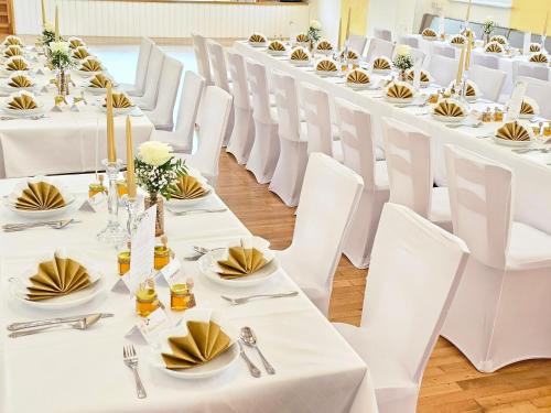a row of white tables and chairs in a room at Gasthof goldener Engel in Kemnath