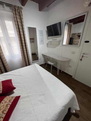 a bedroom with a bed and a table and a television at Lu Bàtil B&B - Rooms in Alghero