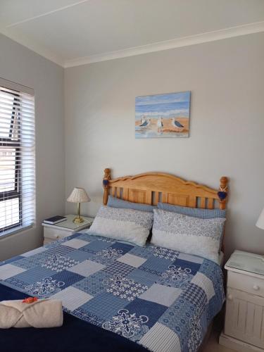 a bedroom with a bed with a blue and white quilt at Hartenbos - Bayview 230m from beach in Mossel Bay
