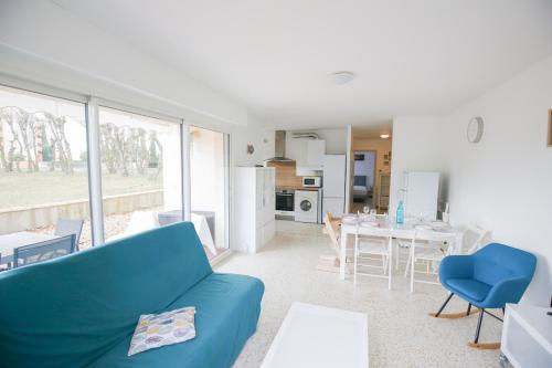 un salon avec un canapé bleu et une cuisine dans l'établissement Le Fenouil, au Grau-du-Roi