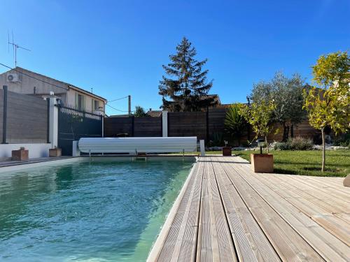 une piscine avec un banc sur une terrasse en bois dans l'établissement Villa avec piscine privée - Capestang, à Capestang