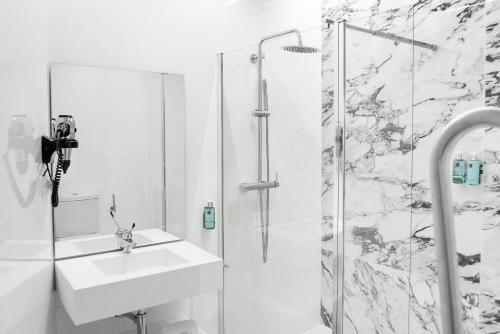 a white bathroom with a sink and a shower at Hotel La Casa de Los Mosaicos by Maxi Hoteles in Granada