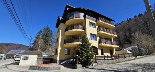 a yellow building with balconies on the side of it at Pensiunea Clasic in Buşteni