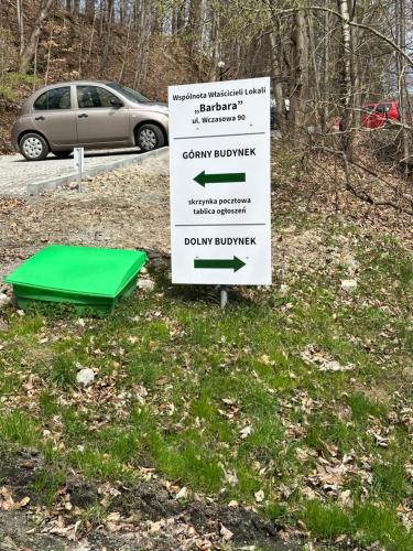 a sign sitting in the grass next to a car at Apartament Zielona Równica in Ustroń