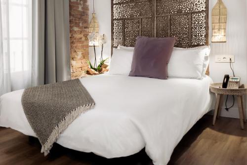 a bedroom with a large white bed with a wooden headboard at Hotel La Casa de Los Mosaicos by Maxi Hoteles in Granada