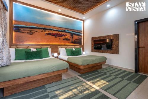 two beds in a room with a painting on the wall at StayVista at Aura Farmstay with Pool & Lawn in Badlapur