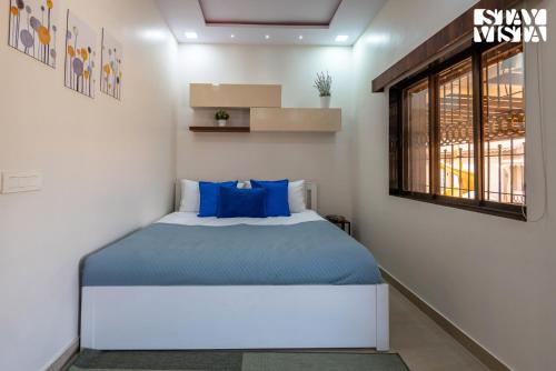 a bedroom with a bed with blue sheets and a window at StayVista at Aura Farmstay with Pool & Lawn in Badlapur