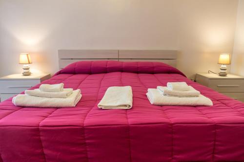 a pink bed with two towels and two lamps at San Pietro's Home - Guesthouse in Rome