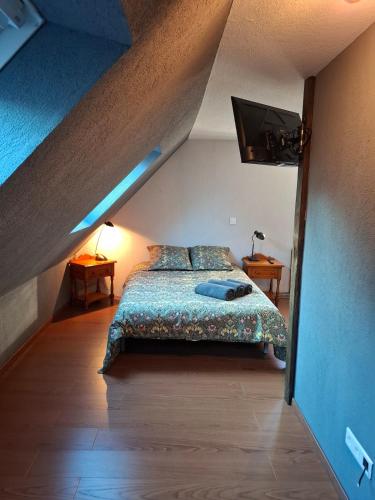 - une chambre mansardée avec un lit et une télévision dans l'établissement Maison d'hotes au coeur du village, à Reichshoffen